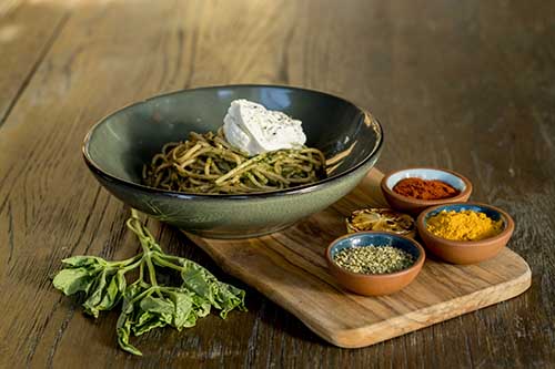 a bowl of pasta arranged with ramekins of spices