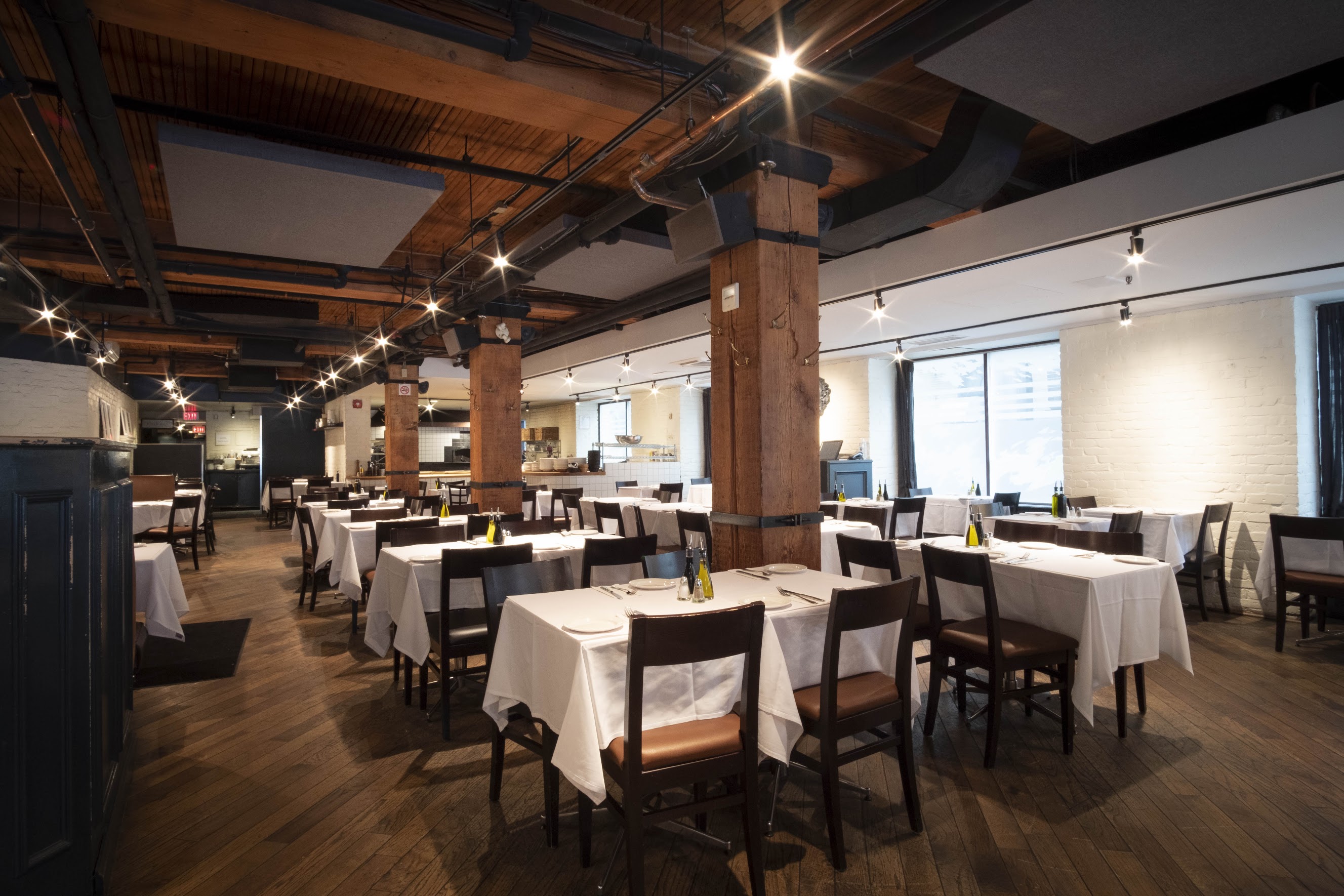 inside of restaurant table seating area with exposed historical wood beams and pillars