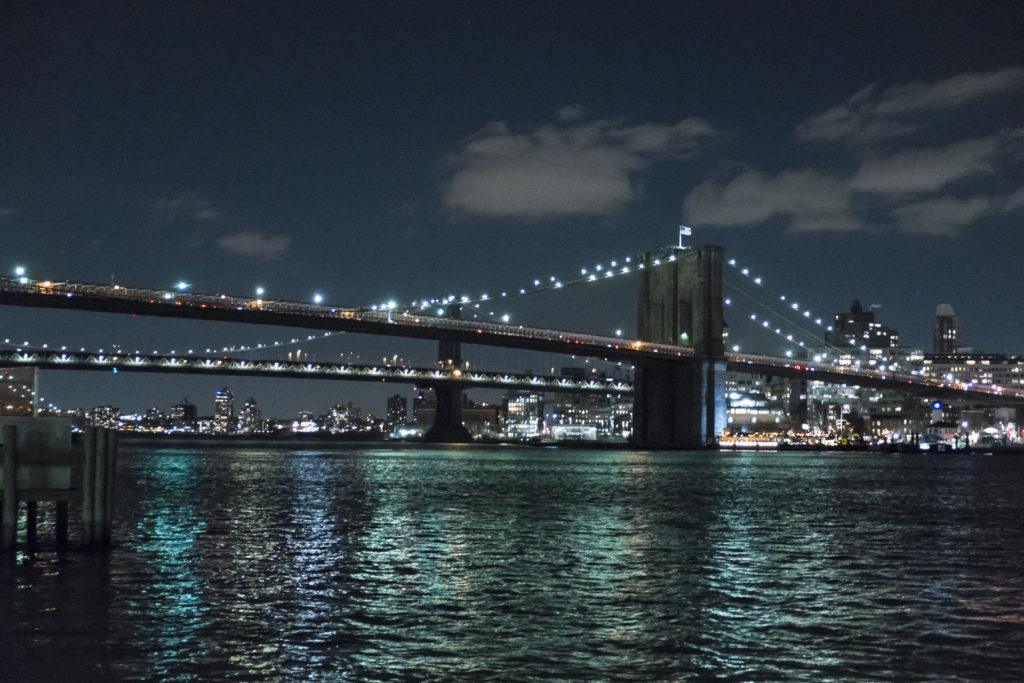 Brookling bridge at night shot from a manhattan peir