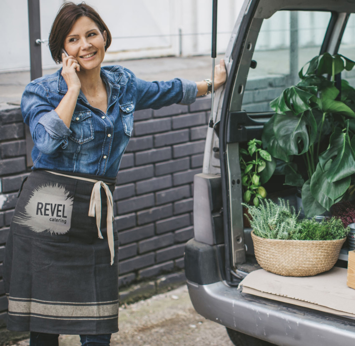 a server unloading a truck with the Revel logo on her apron