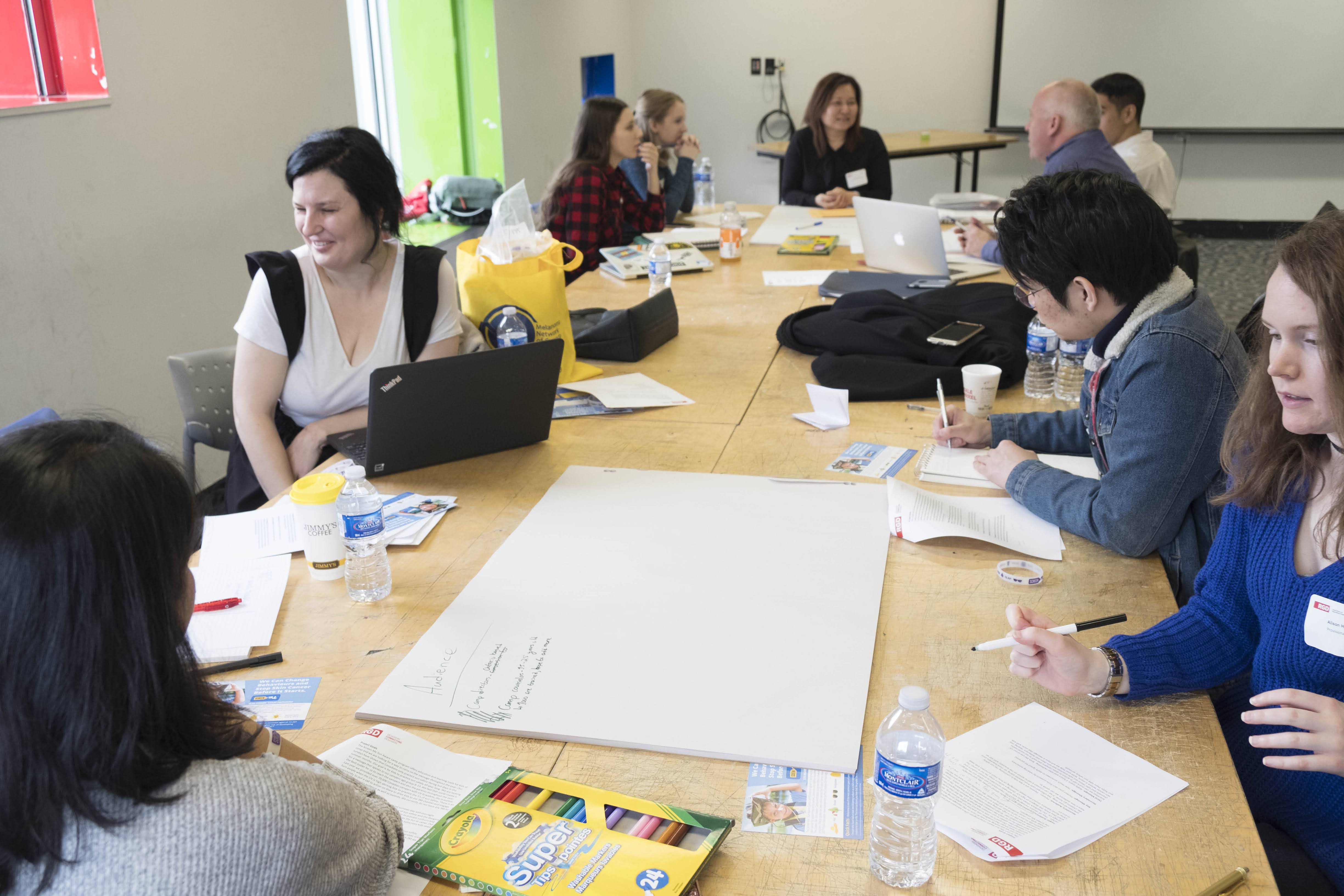 a boardroom table with designers at work and design supplies